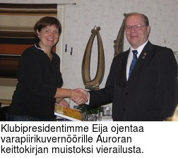 Klubipresidentimme Eija ojentaa varapiirikuvernrille Auroran keittokirjan muistoksi vierailusta.