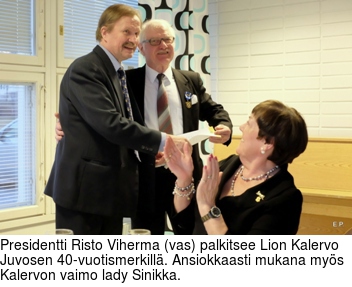 Presidentti Risto Viherma (vas) palkitsee Lion Kalervo Juvosen 40-vuotismerkillä. Ansiokkaasti mukana myös Kalervon vaimo lady Sinikka.