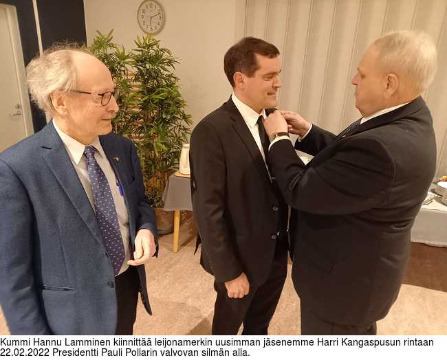 Kummi Hannu Lamminen kiinnitt leijonamerkin uusimman jsenemme Harri Kangaspusun rintaan 22.02.2022 Presidentti Pauli Pollarin valvovan silmn alla.