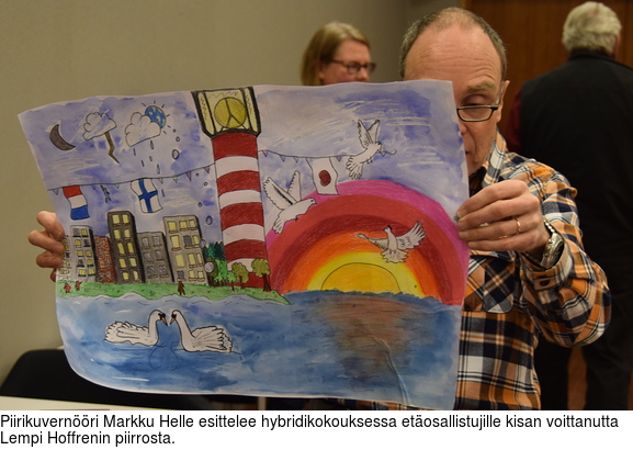 Piirikuvernri Markku Helle esittelee hybridikokouksessa etosallistujille kisan voittanutta Lempi Hoffrenin piirrosta.